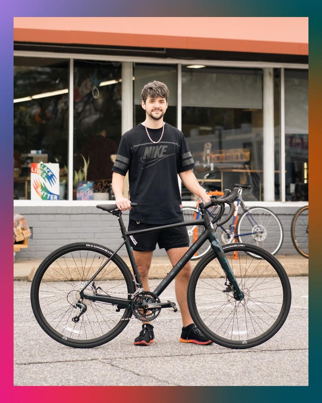 Patrick standing with his black bike.